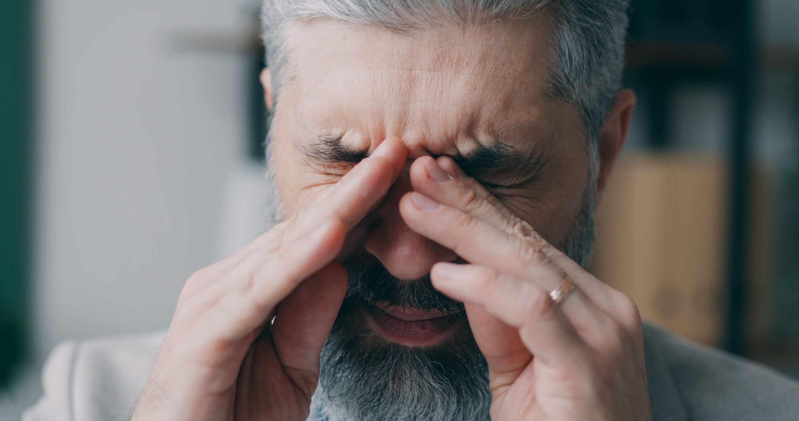 man rubbing sore eyes